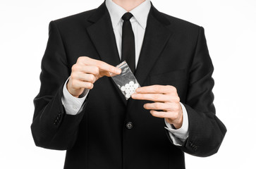 Addiction and business topic: hand in a black suit holds bag with white pills a drug on a white isolated background in studio