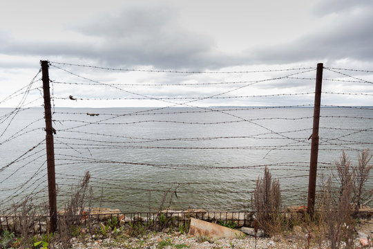 barb wire fence over gray sky and sea