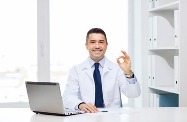 smiling doctor with laptop showing ok in office