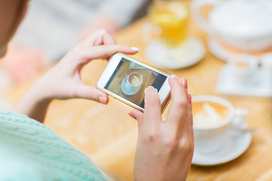 close up of woman smartphone picturing coffee cup
