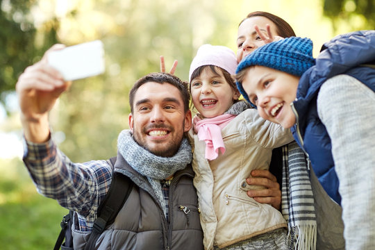 family taking selfie with smartphone outdoors