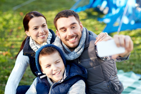 family with smartphone taking selfie at campsite
