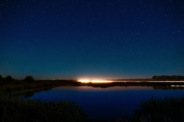 Fototapeta na wymiar The stars in the night sky reflected in the river. The lights fr