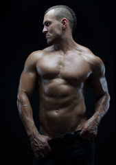 Fototapeta na wymiar Bodybuilder and strip theme: beautiful with pumped muscles naked man posing in the studio on a dark background