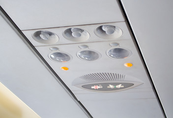 aircraft passenger console overhead, seat belt and no smoking sign