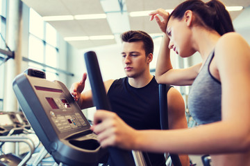 woman with trainer exercising on stepper in gym