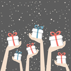 Hands are holding christmas presents with red and blue ribbons on the snowing background.