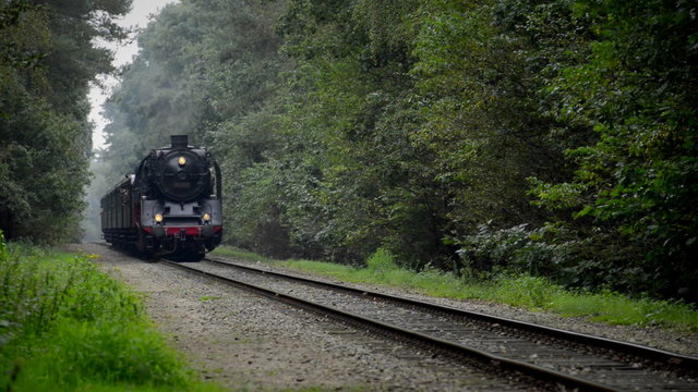 Old steam locomotive pulling railroad cars in the countryside.