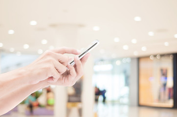 Hand holding smart phone on shopping mall backgrounds
