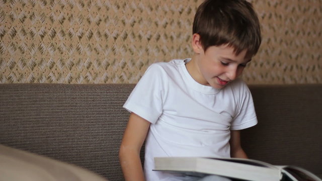 boy reading a book on the couch at home