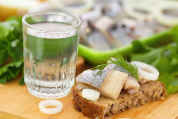 Sandwich with herring fillet and glass of vodka