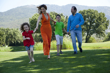 Obraz premium Happy family is running hand-in-hand at park all together