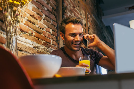 Man Working with a Laptop and And a Mobile Phone while Drinking