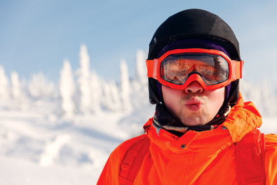 Portrait of a snowboarder in the winter resort in sunglasses mask at ski resort in mountains