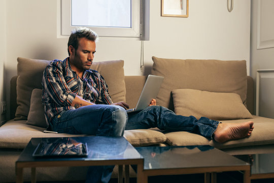 Young Man Concentrated While Using a Laptop at Home