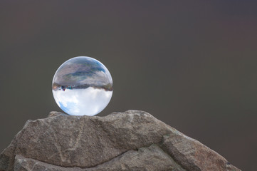 Glass transparent ball on the top of rock and dark background