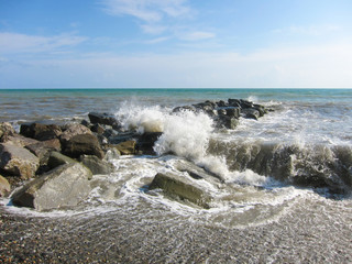 The waves crash with a spray of  rocks