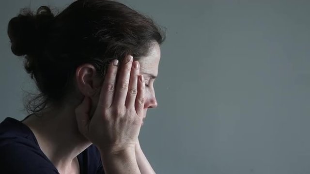 Woman in her thirties sitting at a table upset
