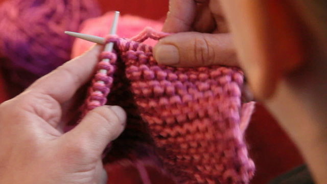 Winter time. Woman hands knitting wool close up. High angle camera view from the shoulders.