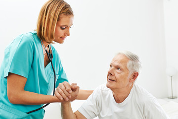 Frau im Pflegeheim hilft Senioren beim Aufstehen