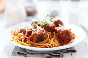 spaghetti and meatballs with oregano garnish on rustic table shot with selective focus