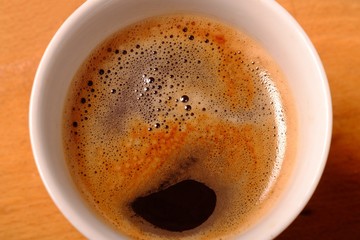 hot black coffee in a white cup with foam
