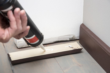 home improvement, pushing glue on the wooden baseboard