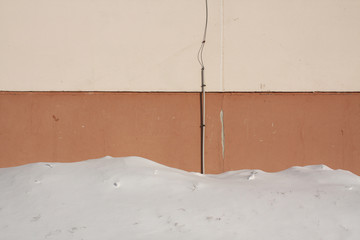 Snow near brown house wall.
