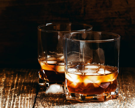 Two glasses of whiskey with ice, dark toned image, selective foc