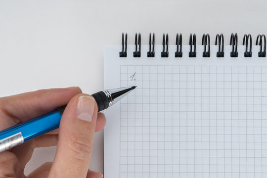 A hand is writing on blank page notebook on white background