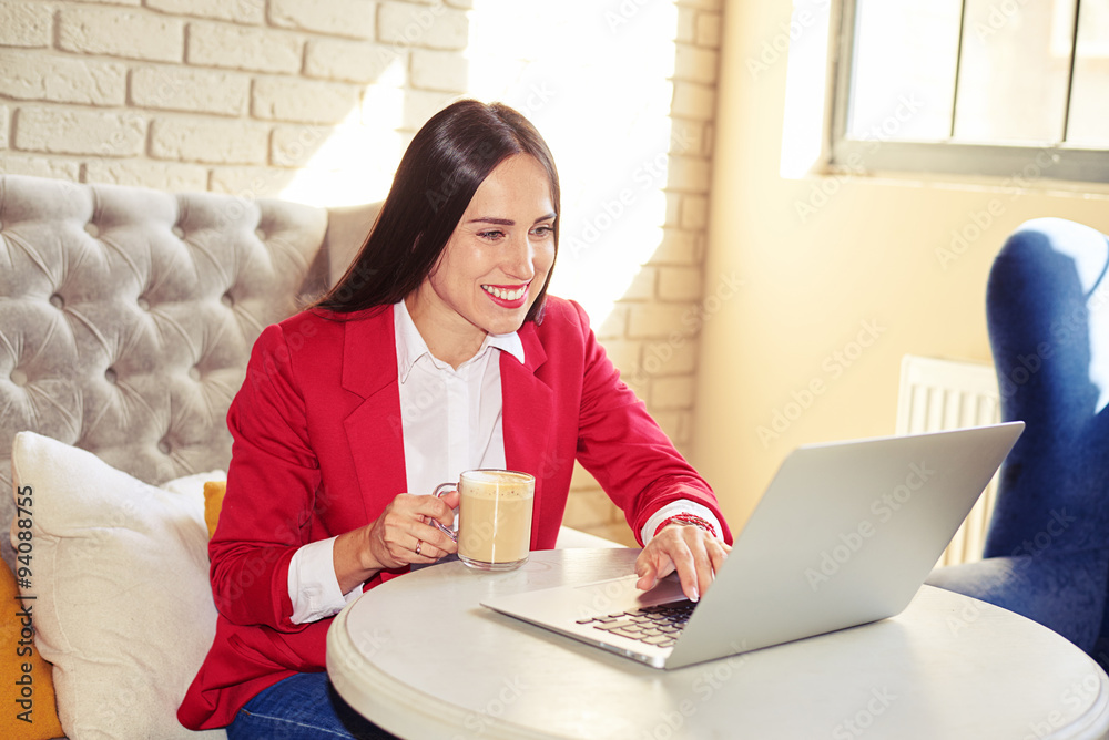 Wall mural cheerful woman with laptop sitting in cafe