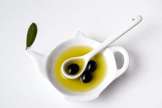 Aceite de oliva con cuchara y aceitunas negras