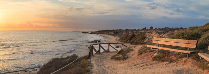 Fototapeta premium Ławka wzdłuż punktu widokowego z widokiem na zachód słońca na Crystal Cove Beach, Newport Beach i Laguna Beach w południowej Kalifornii