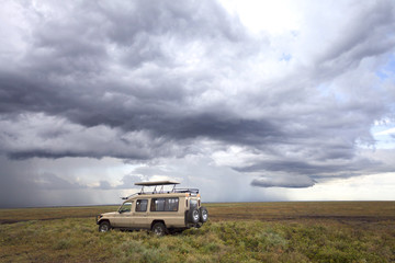 Safari car in the Serengeti Mara savanna before thunderstorm in the rainy season