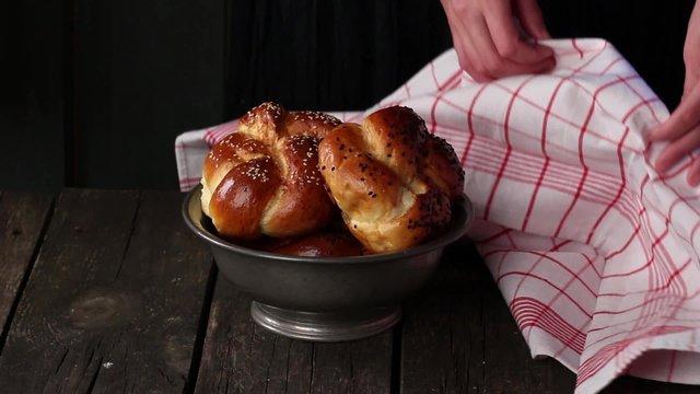 Opening of vintage bowl with fresh baked home made mini challah bread. Dark rustic style.
