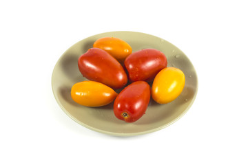 Red and yellow tomatoes on a green plate isolated on white
