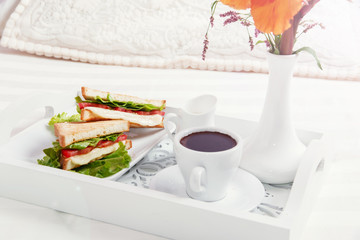 breakfast on wooden tray in bed sandwich and coffee