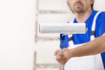 Close up shot of painter man aiming at you with paint roller. © guerrieroale