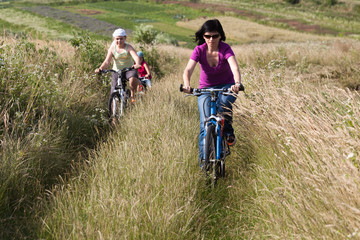 Family riding a bicycles in the meadow