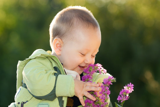 happy baby boy smell flowers, outdoors