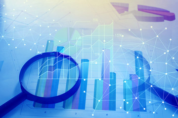 Magnifying glass and documents with analytics data lying on tabl