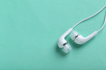 White headphones on a mint paper background