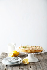 Lemon meringue pie on cake stand on grey wooden background