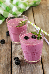 Blackberry smoothie in the glasses on grey wooden background