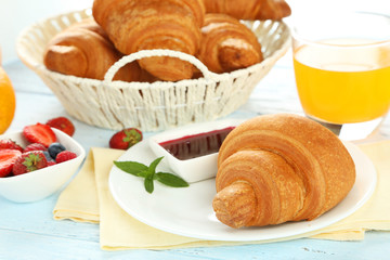 Fresh tasty croissants with berries on blue wooden background