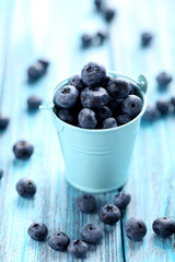 Tasty blueberries in bucket on a blue wooden table
