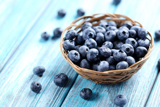Tasty blueberries in basket on a blue wooden table