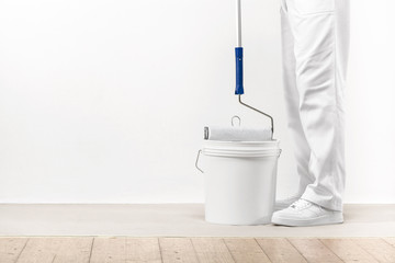 Painter man takes the color with paint roller from the bucket. - 94095988