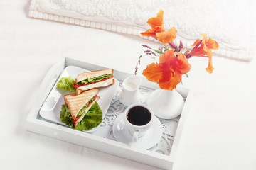 breakfast on wooden tray in bed sandwich and coffee