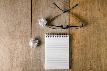 Blank notepad and eye glasses on wooden table